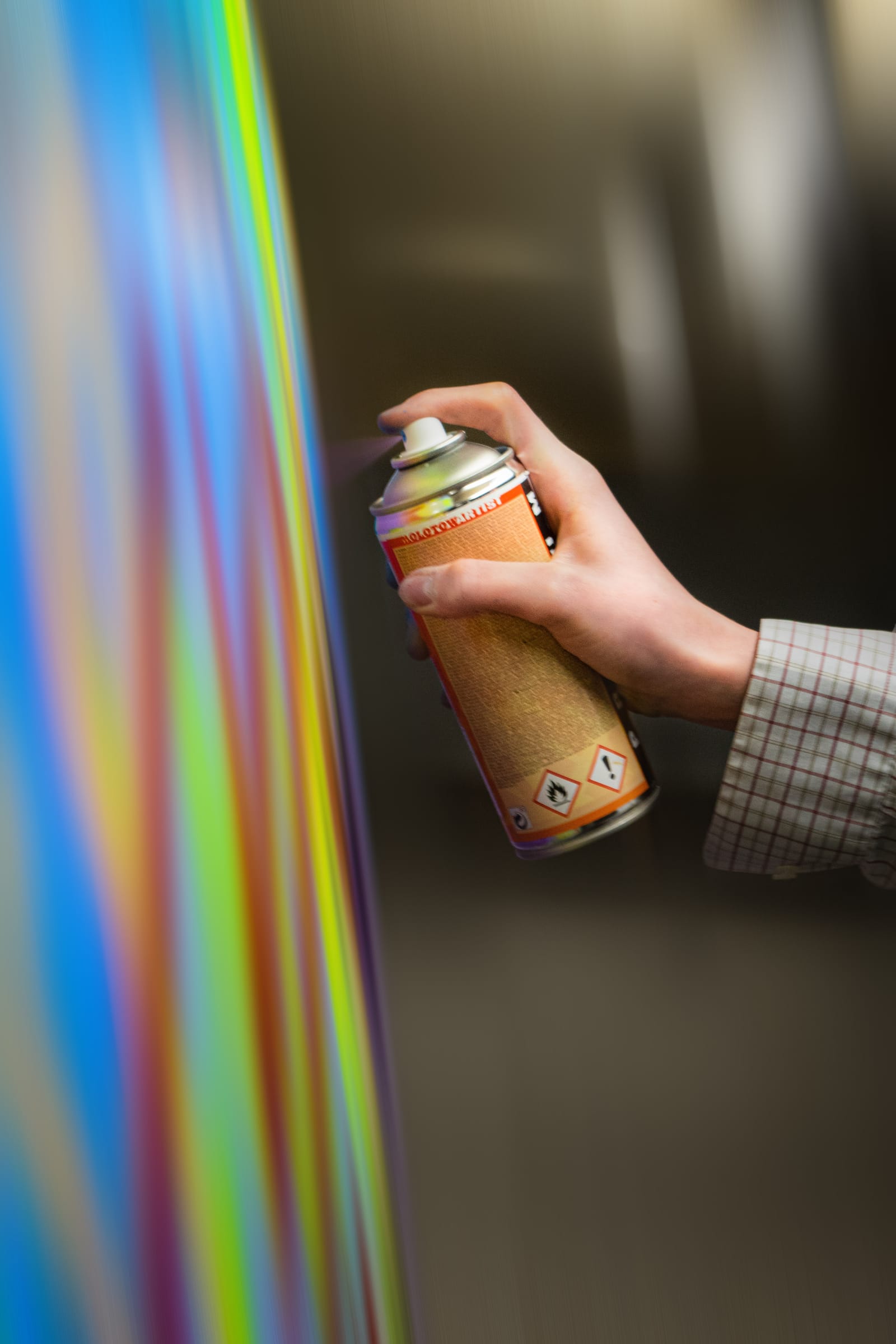Studio shot: hand holding a spray can behind a prismatic light streak