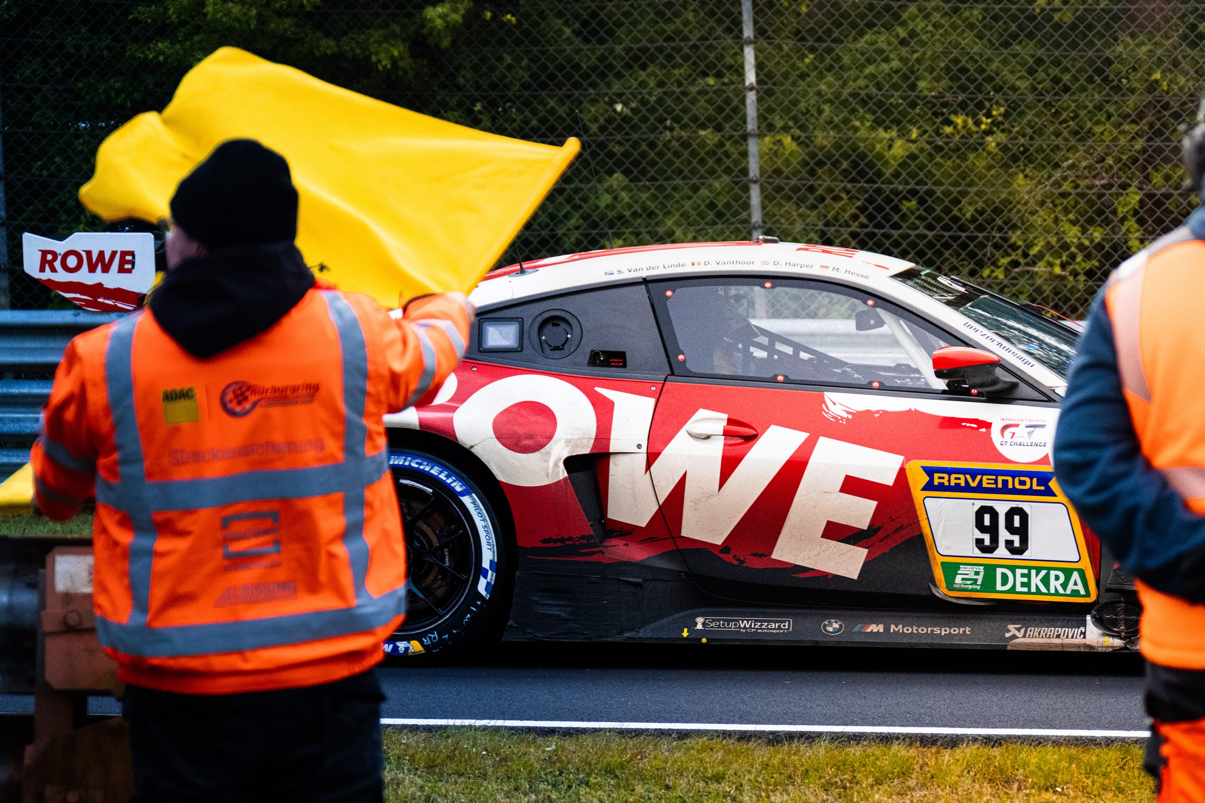 Marshal waving a yellow flag in front of a GT race car