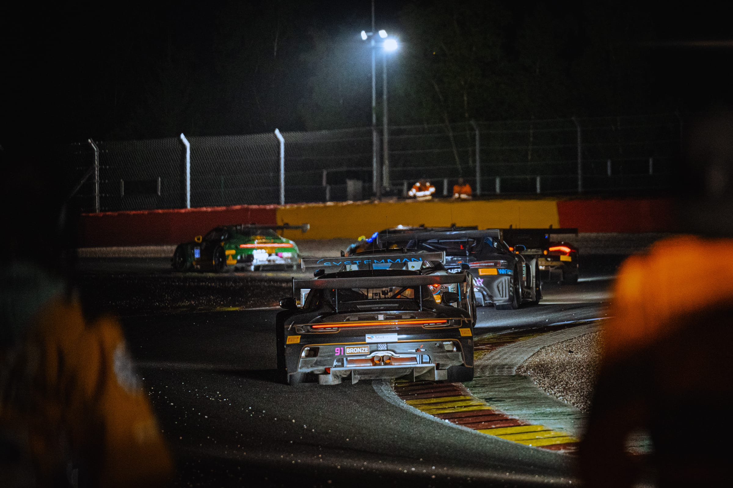 GT race cars at night on track under floodlights