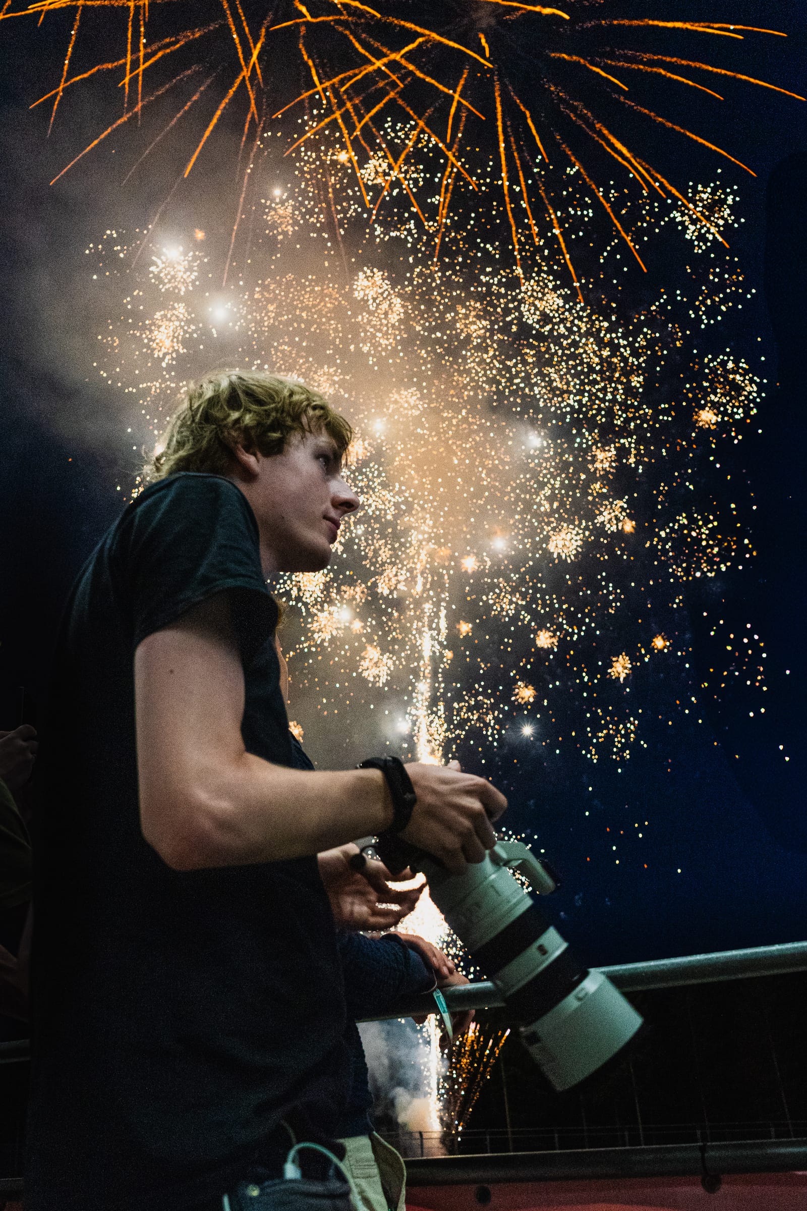 Photographer with a telephoto lens in front of a shower of sparks at night